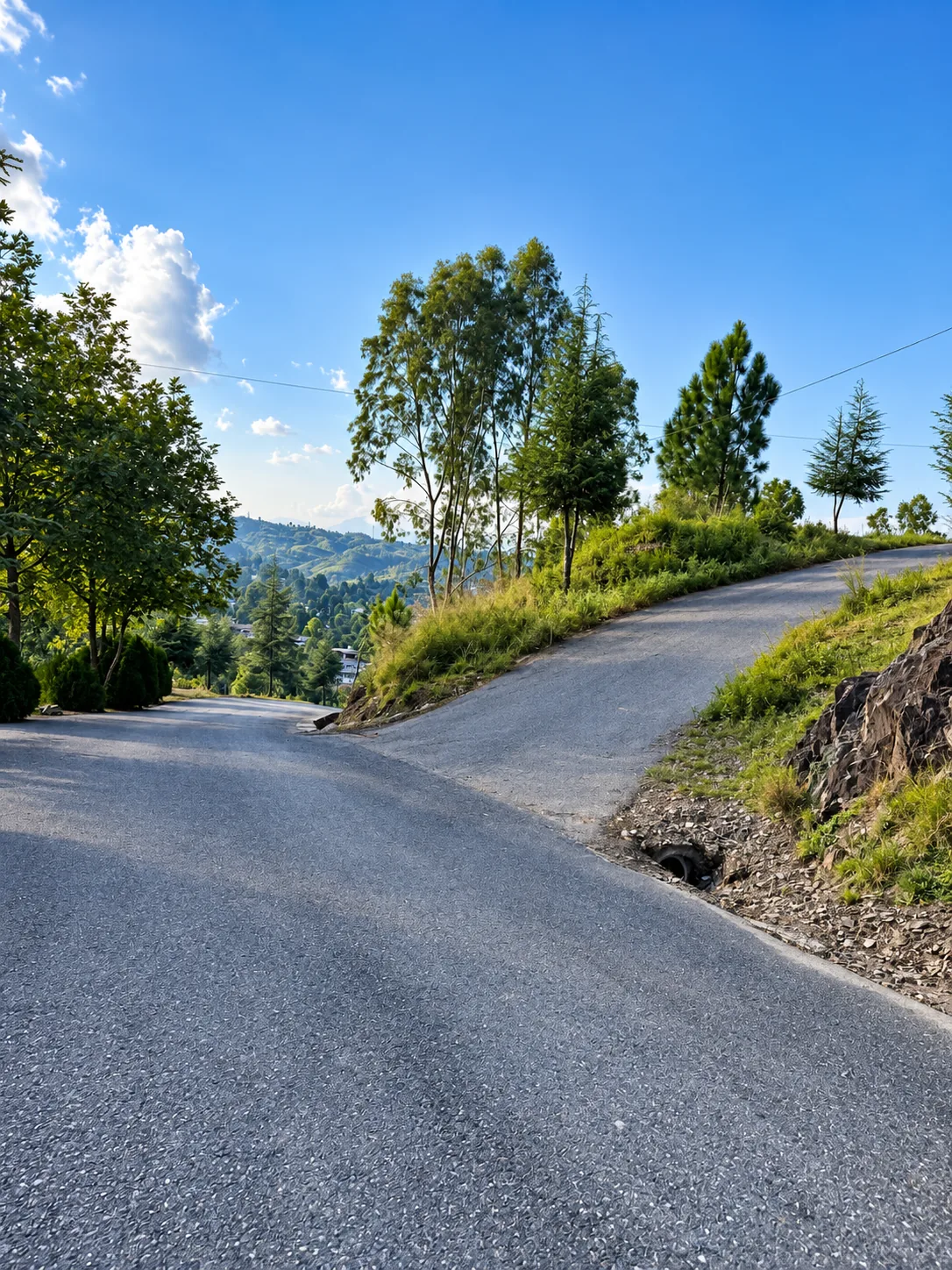 A wide paved road with a fork and valley panorama